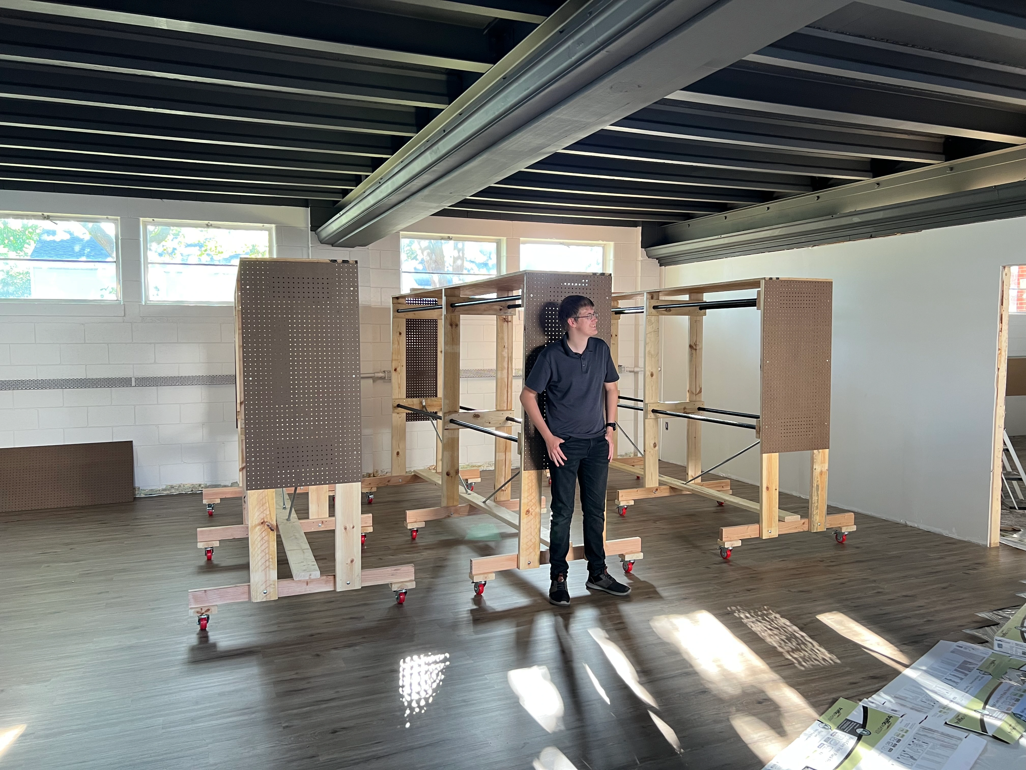 Joshua Stephen Miller standing infront of the three clothing racks he created for his Eagle Scout project inside Resources of Hope
